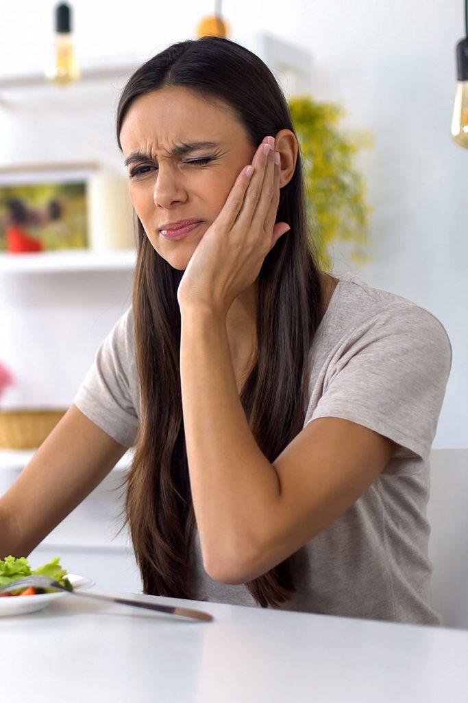 mujer sufre dolor de dientes y problemas bucodentales