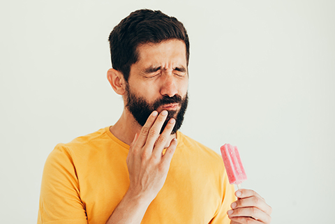 hombre con sensibilidad dental al comer un helado