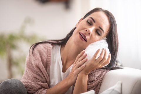 mujer calmando dolor de dientes con hielo