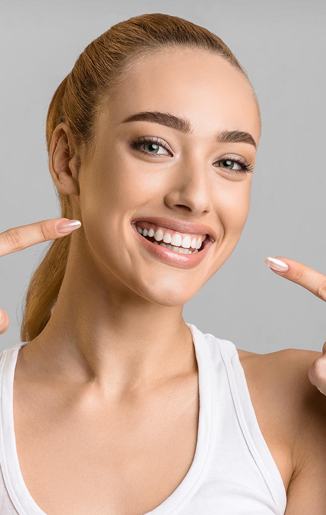 mujer joven rubia sonriendo tras tratamiento de estética dental