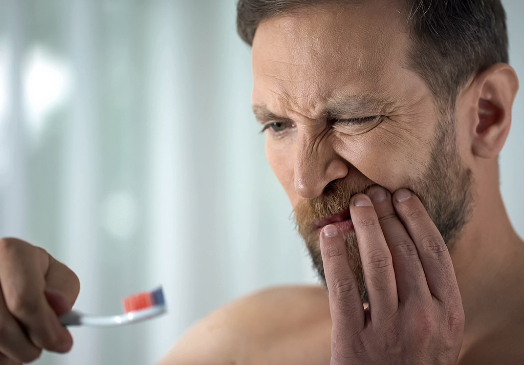 hombre adulto sufre dolor al cepillarse por periodontitis